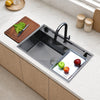 Oslo Honeycomb Gunmetal workstation sink with black pull-down faucet and a defrosting tray on the sink, with a cutting board on the counter