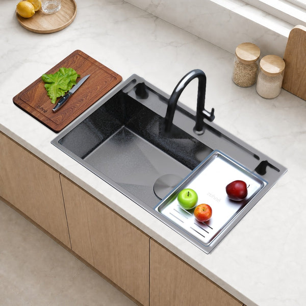 Oslo Honeycomb Gunmetal workstation sink with black pull-down faucet and a defrosting tray on the sink, with a cutting board on the counter