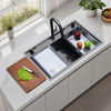 Oslo Lunar Gunmetal workstation sink with black pull-down faucet, a defrosting tray and soak and rinse bin on the sink, with a cutting board on the counter